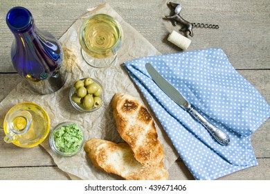Two toast on a brown parchment on old rough boards. Blue bottle of wine, the wine in the glass, olives and butter, olive oil in a bottle. View from above - Powered by Shutterstock