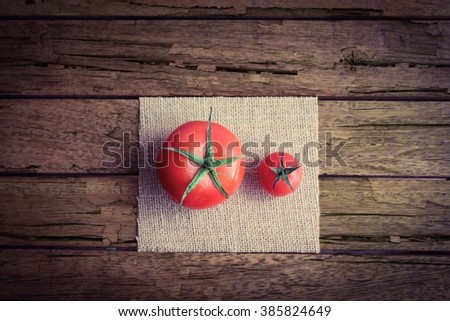 Two tomatoes of two different sizes on a rough wooden table