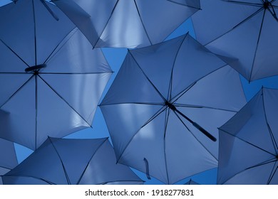 Zwei tonblauer bunter Hintergrund. Farbige Regenschirme fliegen am Himmel. Dekoration mit buntem Regenschirm auf der Straße mit blauem Himmelshintergrund. – Stockfoto