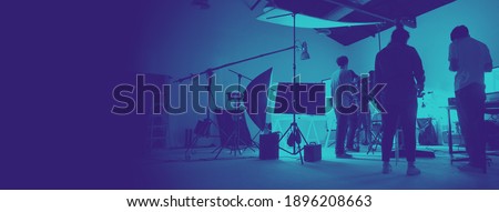 Two tone images of behind the scene of photo shooting production set up in the big studio. Professional crew team working and camera equipment in silhouette. And copy space added.