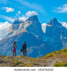Two tourist, a man and a woman, looking upon a viewpoint of the Andes peaks of Cuernos del Paine, Torres del Paine national park, Puerto Natales, Patagonia, Chile.