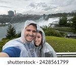 Two Tourists Taking a Selfie at the Niagara Falls, wearing Rain Ponchos