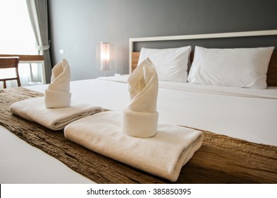 Two towels on the bed in hotel room.