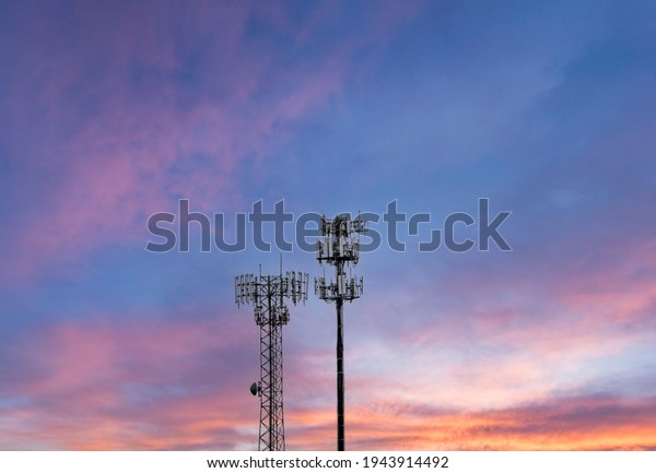 Two\
towers providing cellular broadband and data service to rural areas\
against the sunset. Illustrates digital\
divide.