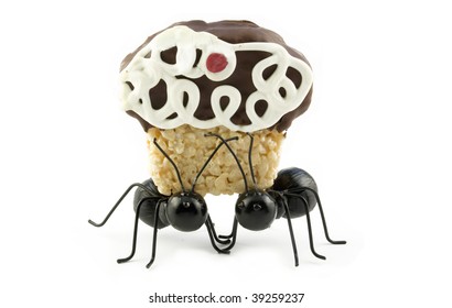 Two toy black ants carrying a crispy treat cupcake, concept, isolated on white with copy space
