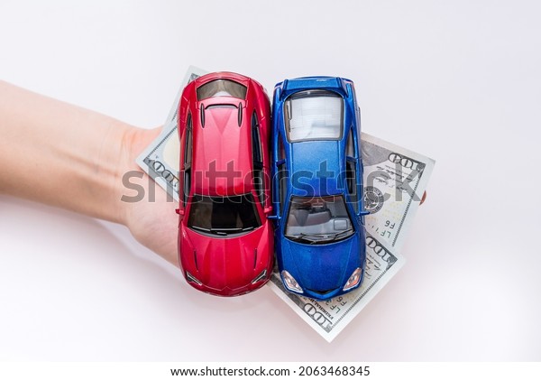 two toy cars with\
cash in hand.  isolated