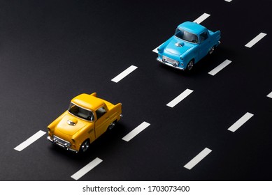 Two Toy Cars On The Road One After Another. One Is Blue One Is Yellow Colored. The Image Tells About Following Distance In Traffic.