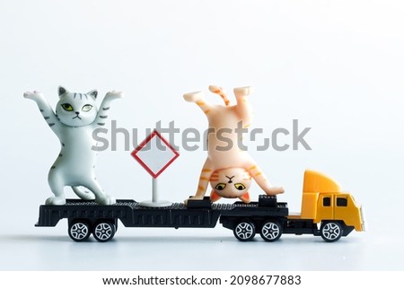 Two toy kittens show circus acrobatic performances on a truck with a trailer. The concept of a traveling circus or circus tent, shapito. White background. Free space for an inscription. Close-up