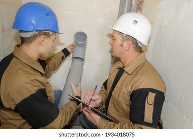 two tradesmen are installing pipes