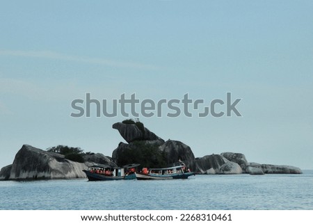 Two traditional boats with full of tourists inside cruising around near the iconic Garuda-shaped stone island in Belitung, Indonesia. 