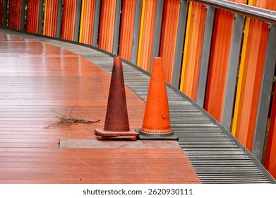Two traffic cone objects for caution warning bridge hole damages isolated on horizontal ratio orange fence background.