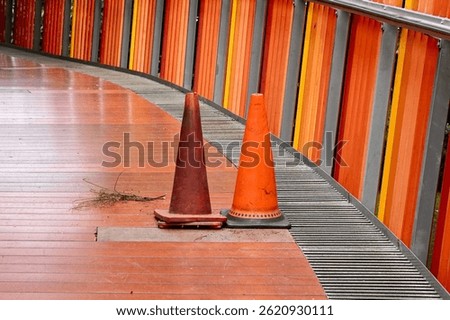 Two traffic cone objects for caution warning bridge hole damages isolated on horizontal ratio orange fence background.