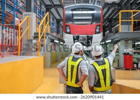 Two train maintenance engineers in a depot, discussing the upkeep of a modern passenger train.