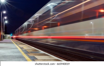 Two Trains Passing Through A UK Station At High Speed In Opposite Directions Captured As Motion Blur