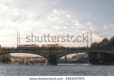 Two trams crossing a bridge over the Vltava river with rowers enjoying the water in Prague. Czech Republic