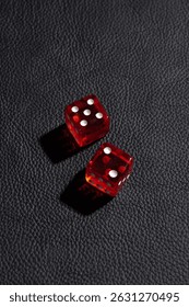 Two translucent red dice on a black leather surface with 4-dot faces. The other die has 2 dots. Both dice cast dark shadows to the bottom.