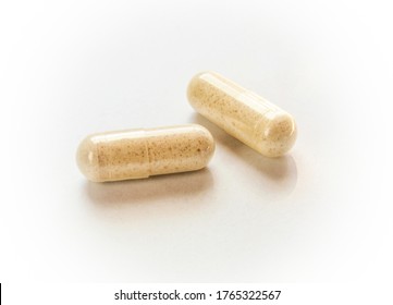 Two transparent capsules filled with brown powder on white 