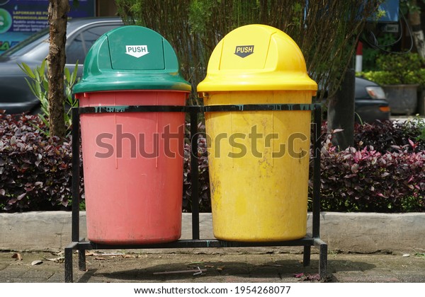 Two trash cans in red and yellow are in the city\
park. Trash cans are divided into two types, organic waste and\
inorganic waste.