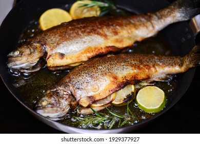 Two trout with rosemary and lemon in a frying pan