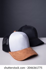 Two Trucker Caps On The Table For Brand Design Application. Tricolor Cap And All Black Cap For Mockup Logo Design.