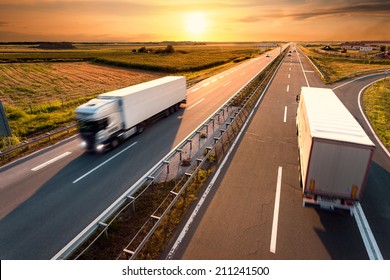 Two trucks on highway in motion blur at sunset