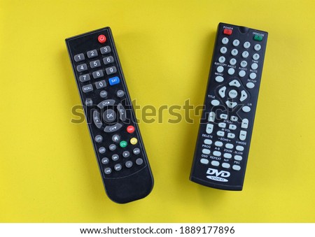 two TV remote isolate on yellow background.concept of watching TV