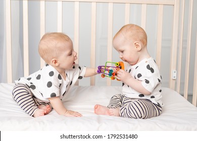two twin babies 8 months old play in the crib, early development of children up to a year, the concept of the relationship of children of brother and sister, the child takes the toy from the other