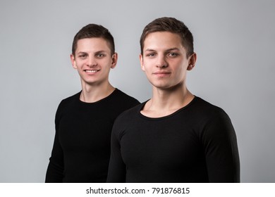 The two twin brother stand on the gray background.