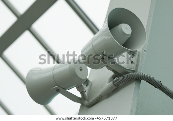 Two twin\
megaphone on the wall of a\
building.