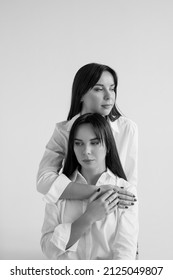 Two Twin Sisters In White Shirts And Blue Jeans