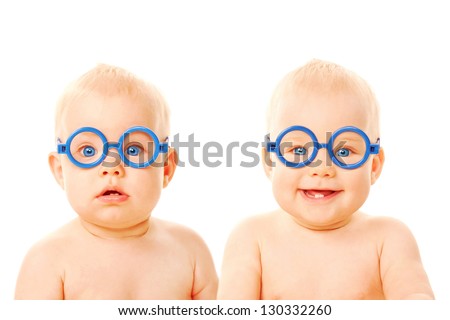 Two twins babies boys wearing glasses. One kid serious, the other child smiling. Young students. Isolated on white background