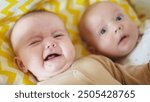 two twins lie in a bed. happy family kid dream concept. cute twins fun lie in bed in the bedroom in the evening smile look at the toy newborn boy and girl brother and sister