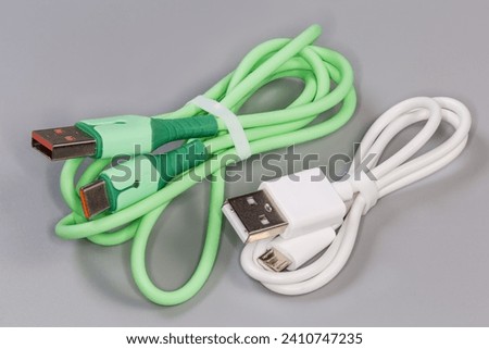 Two twisted USB cables with plugs standard A on one edge and green with plug standard C and white with plug micro-B at the other edges on a gray surface 
 Stock photo © 
