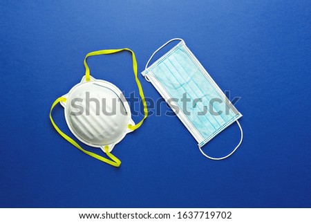 Two types of protective face masks on blue background. Protective masks as precaution in spread of coronavirus 2019-nCoV, Wuhan virus, flat lay