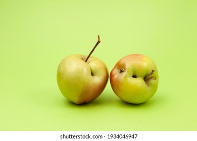 Two ugly apples with flaws on light green background. Selective focus, copy space. Concept - Food waste reduction. Using in cooking imperfect products.