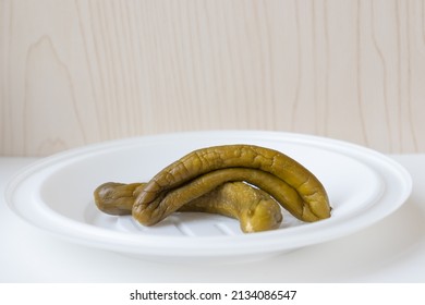 Two Ugly Fermented Pickles Are Rotting On A White Plate