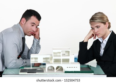 Two Uninspired Architects Sat By Model Housing