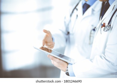 Two unknown doctors with stethoscopes discussing medical exam resoults, standing at hospital office. Physicians use a computer tablet for filling up medication names records. Perfect medical service - Shutterstock ID 1801246690
