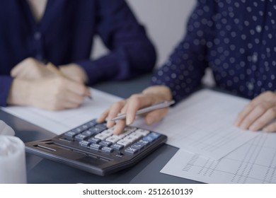 Two unrecognizable accountants or auditors reviewing financial documents in office. Audit and taxes - Powered by Shutterstock