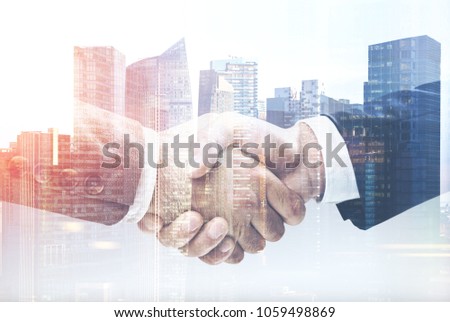 Two unrecognizable businessmen shaking hands in a modern city. Partnership concept. Toned image double exposure