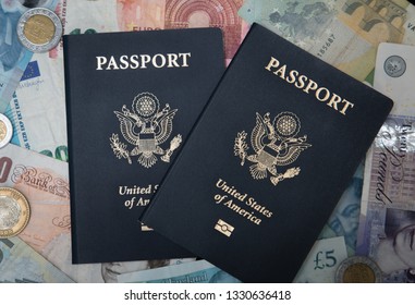 Two USA Passports With A Backdrop Of Foreign Currency Meant To Illustrate Foreign Exotic Travel Around The World