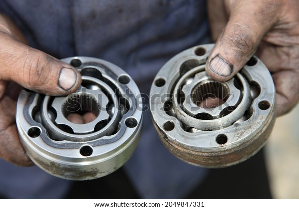 Two used CV joint tripods\
close up in serviceman dirty hands, CV joints replacement car\
repair service