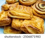 Two variety of miniature baked pastries stacked up on a serving plate. Popular western style breakfast buffet items finished in glazed golden brown. Catering concept.