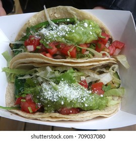 Two Veggie Tacos Filled With Guacamole, Tomatoes, Shredded Lettuce, Onion, Chives, Topped In Parmesan Cheese 