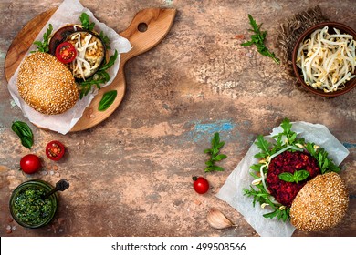 Two Veggies Burgers On Cutting Board Over Stone Vintage Background. Vegan Grilled Eggplant, Arugula, Sprouts And Pesto Burger. Veggie Beet And Quinoa Burger. Top View, Overhead, Flat Lay. Copy Space