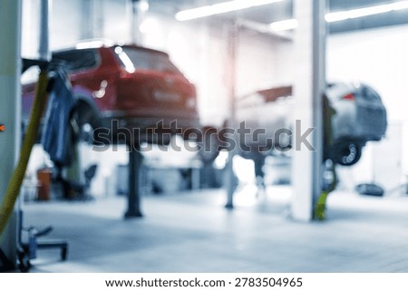 Two vehicles elevated for maintenance in auto repair shop, blur background.