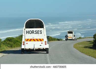 Two vehicles on the road transporting horses in horseboxes to the beach.