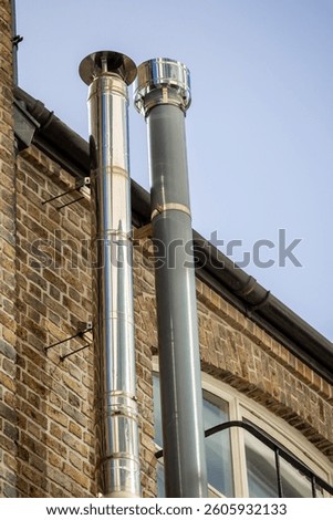 Two vertical chimney flues attached to a brick building facade.