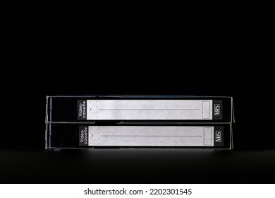 Two VHS video tapes with blank label isolated on black background. Two vintage VHS tapes for retro media object.