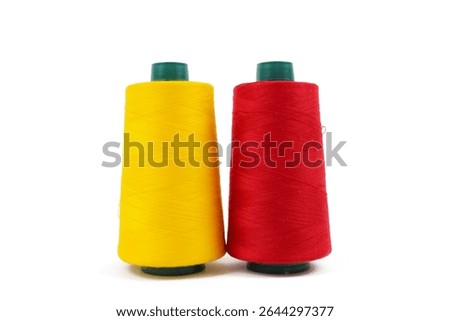 Two vibrant spools of thread, one bright yellow and one vivid red, stand upright against a clean white background.